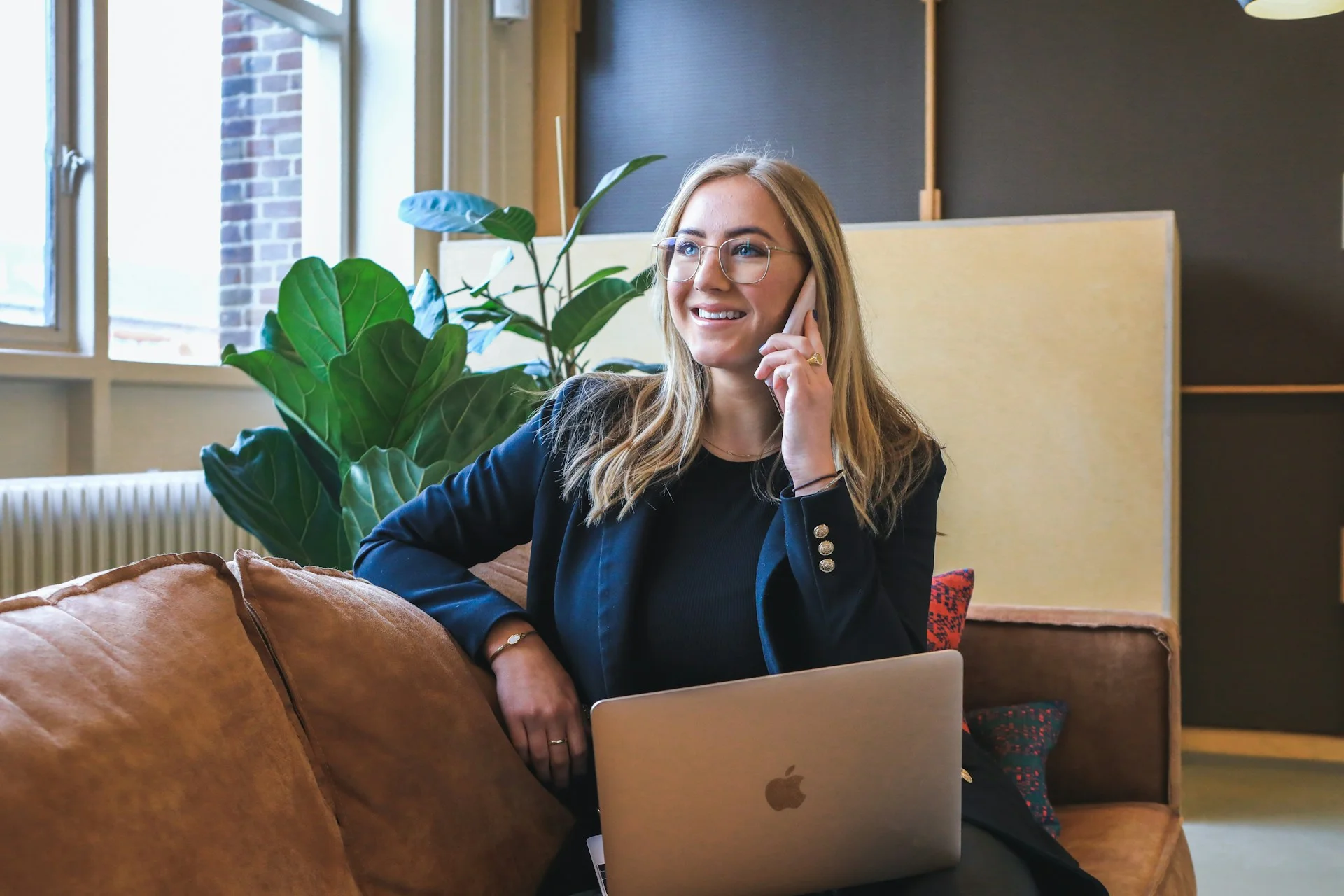 airbnb-management-in-the-UK-woman-sitting-on-the-phone-smiling-laptop-brown-chair